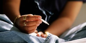 Teenager (16-18) smoking hand rolled cigarette
